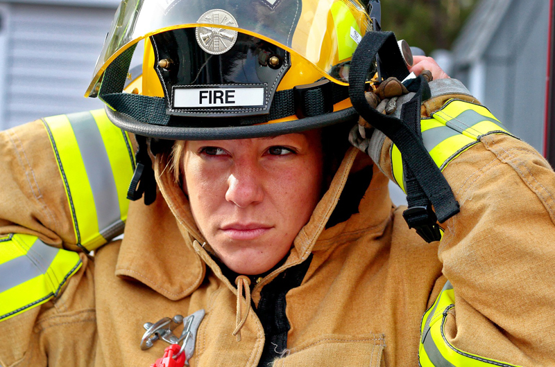 A woman firefighter putting on her helmet